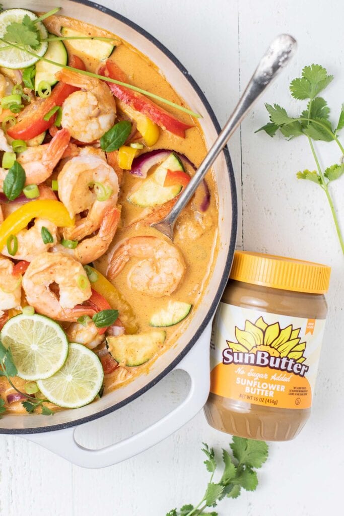 A jar of SunButter sitting to a thai curry.