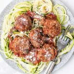 Air Fryer meatballs shown served over a plate of zoodles with marinara sauce.