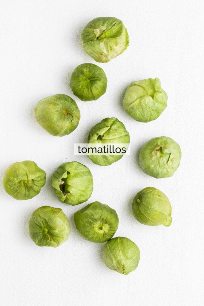 A pound of tomatillos shown with the papery husks still covering them.