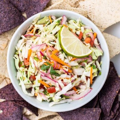 A close up look at a bowl of cabbage salsa surrounded by chips.