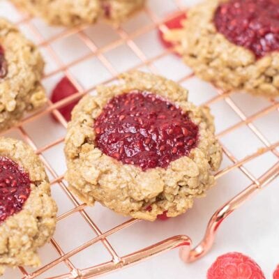 A close up look at a raspberry thumbprint cookie on a cooling rack.