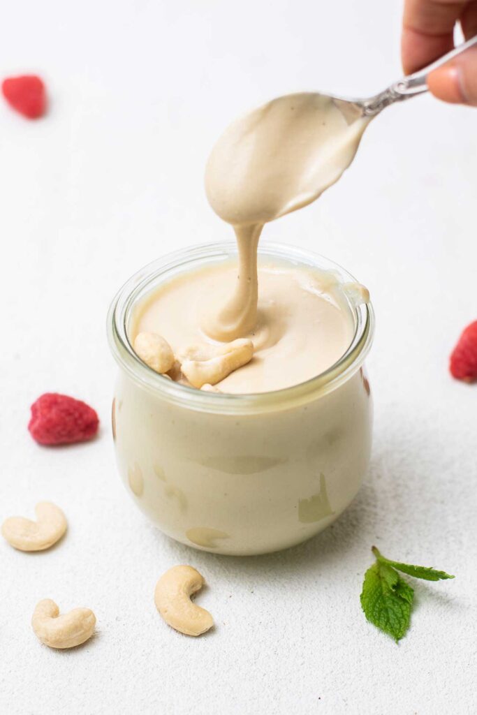 A spoon with cashew butter, showing the silky, drippy texture.