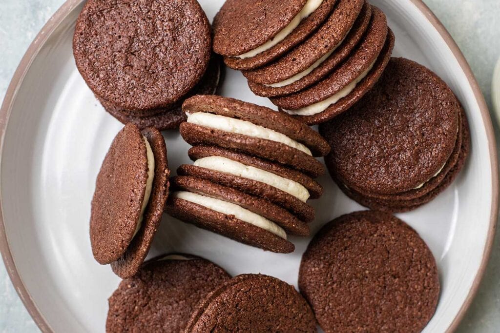 A plate piled with gluten free oreo cookies showing the vanilla cream filling.