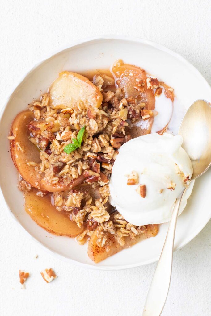 A bowl of gluten free apple crisp shown with ice cream.