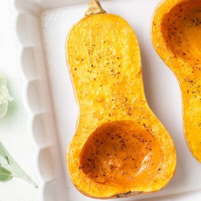 Butternut squash halves shown in a baking dish browned around the edges.