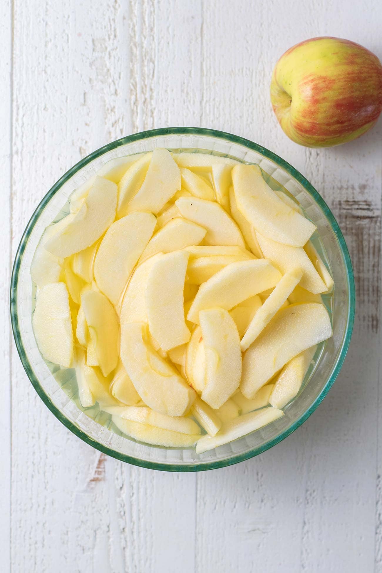 Apple slices shown soaking in lemon water.