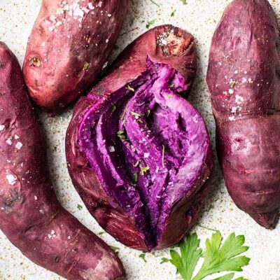 A plate of baked purple sweet potatoes, showing the vibrant purple flesh.
