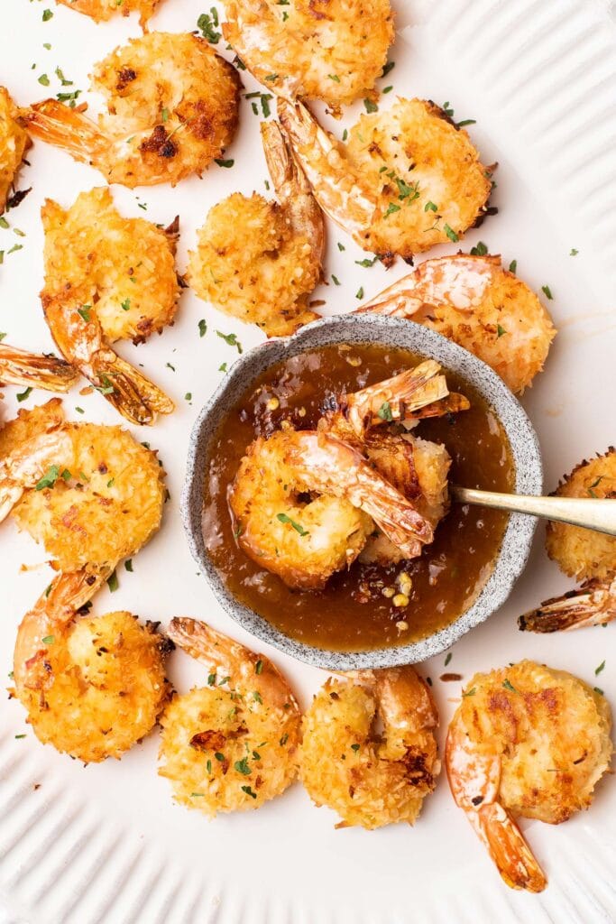 Gluten free coconut shrimp shown being dipped in a chili apricot dipping sauce.