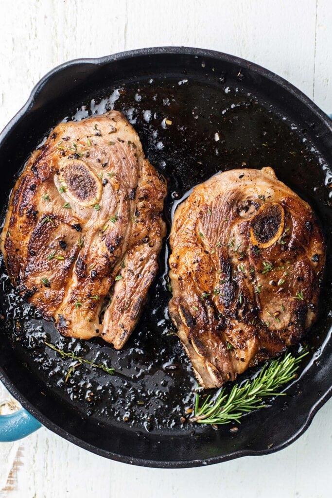 Lamb shoulder chops shown seared with a nice crust in a skillet.