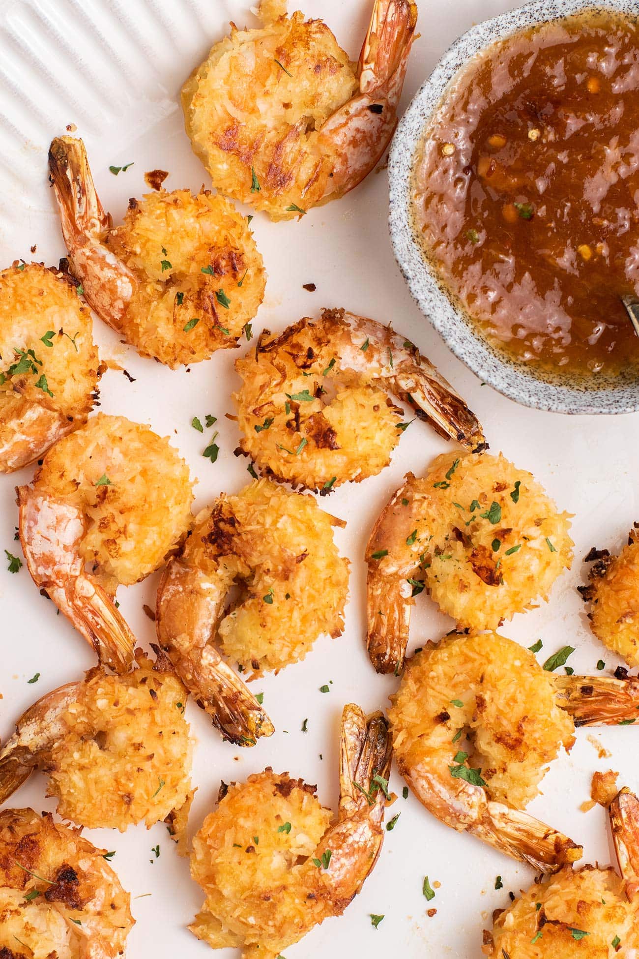 A platter of crispy baked coconut shrimp shown with an apricot dipping sauce.