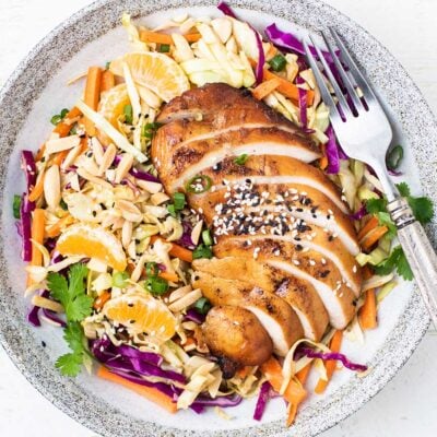 A colorful cabbage salad topped with marinated chicken.