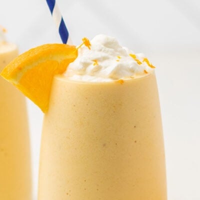 A close up look at an orange smoothie topped with whipped cream.