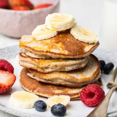 Buckwheat pancakes shown drizzled with honey and topped with banana.