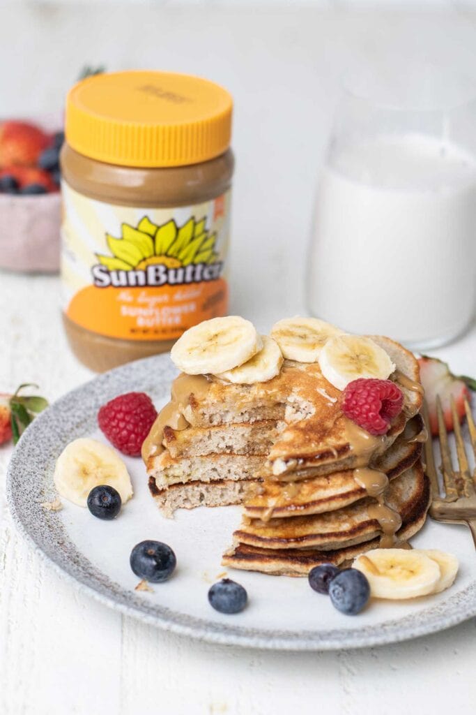 A plate of pancakes sitting with a jar of SunButter.