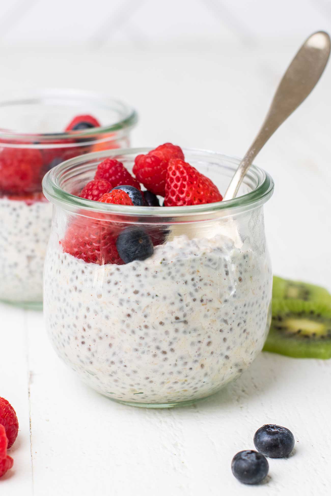 A jar of overnight oats with yogurt and chia seeds shown topped with berries.