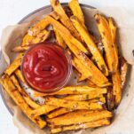 A plate with air fryer sweet potato fries and a little dish of ketchup.