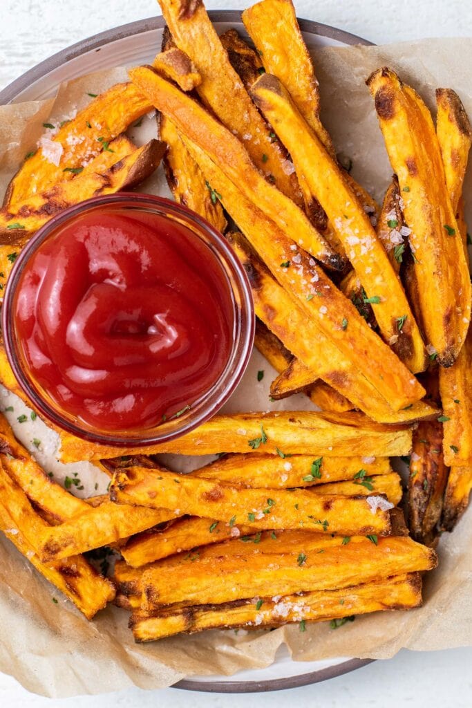 A plate with crispy air fryer sweet potato fries served with ketchup.