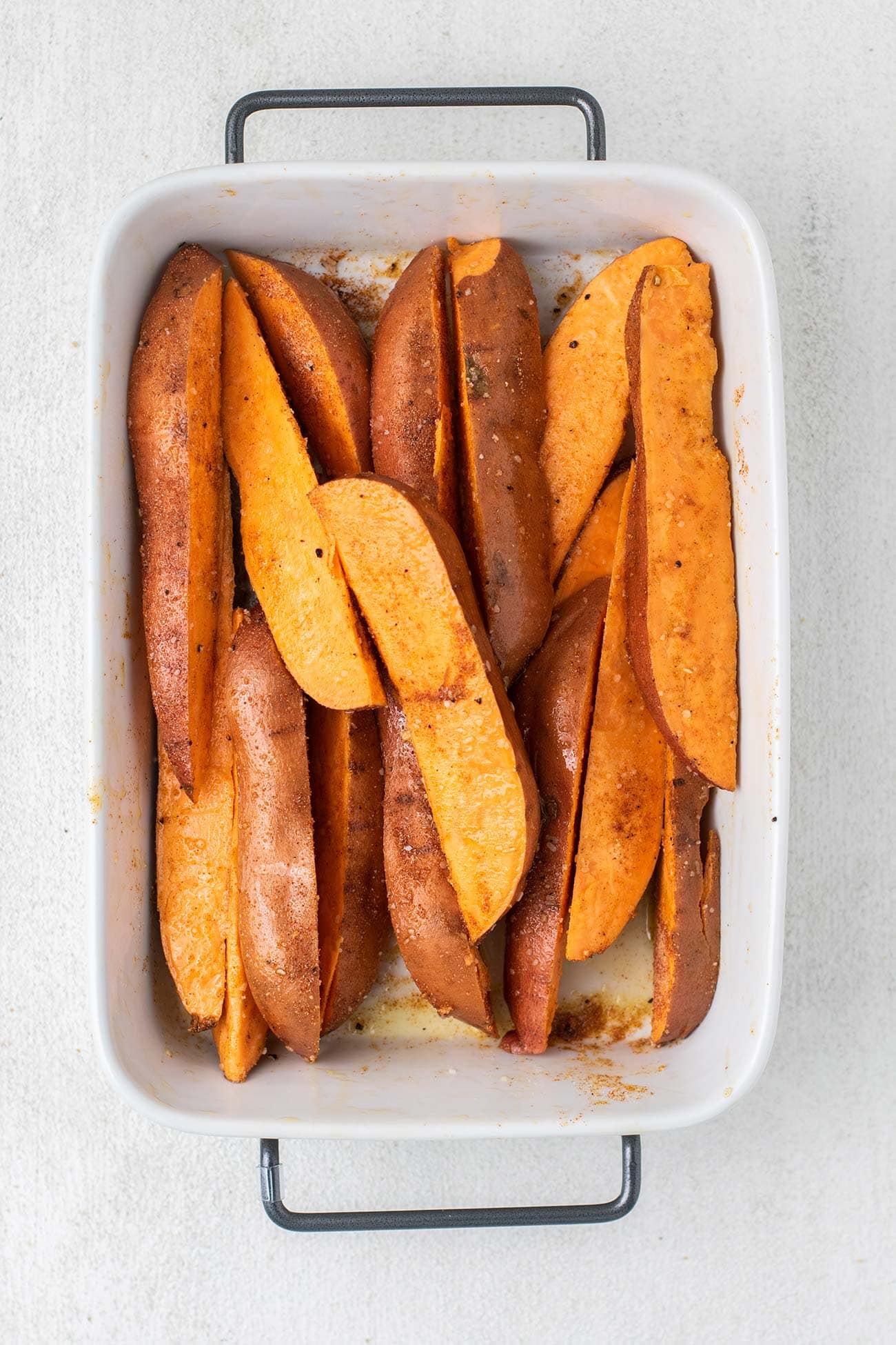 Sweet potato wedges shown with a seasoning rubbed into them.