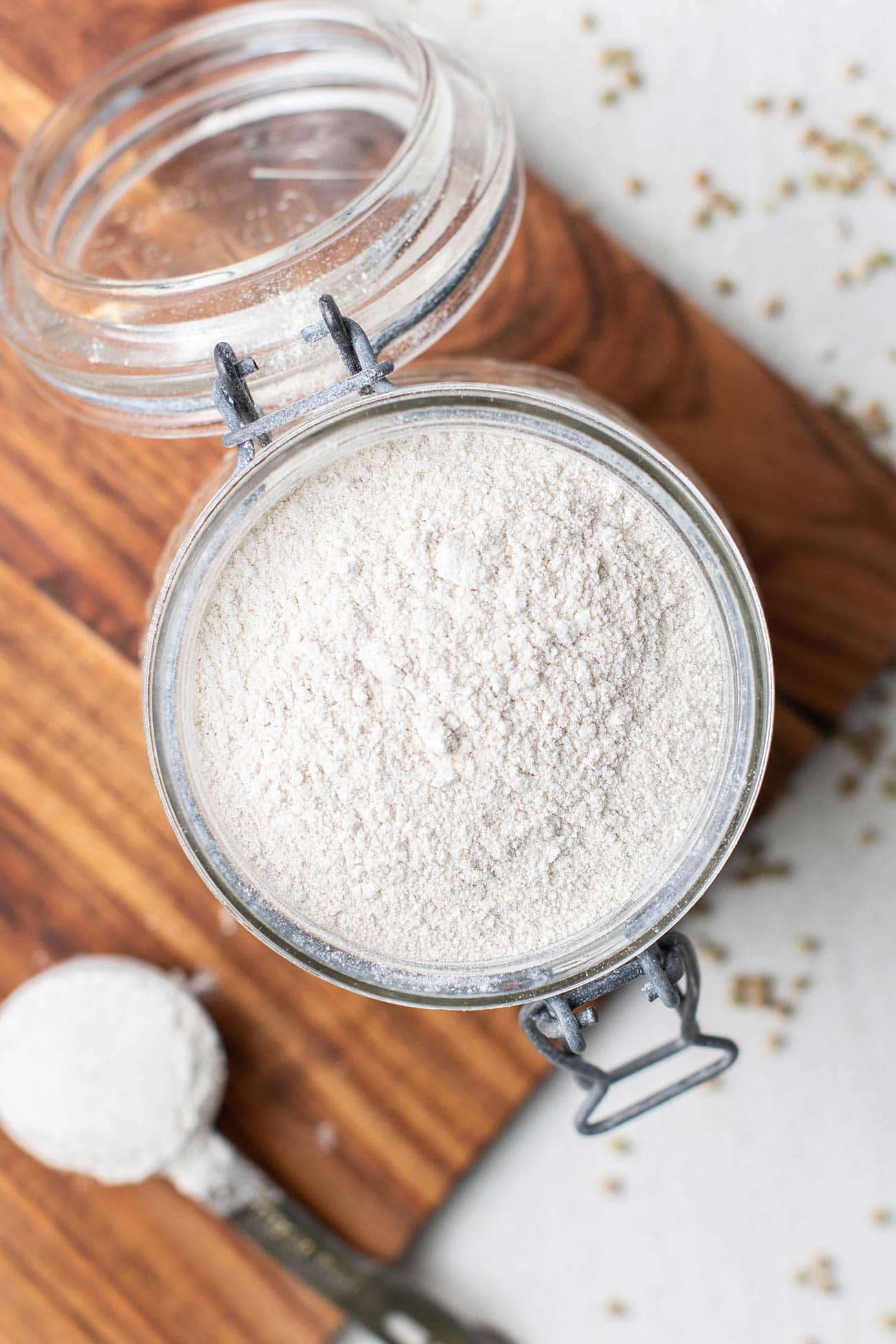 A container of buckwheat flour shown with whole buckwheat groats on the countertop.