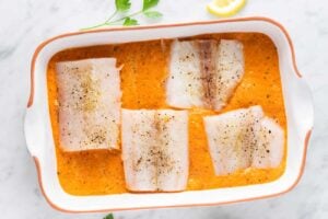 Add cod fillets to the baking dish filled with red pepper sauce.