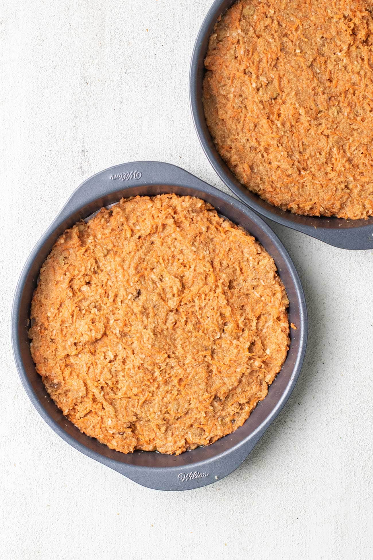 The carrot cake batter spread into two layer cake pans.