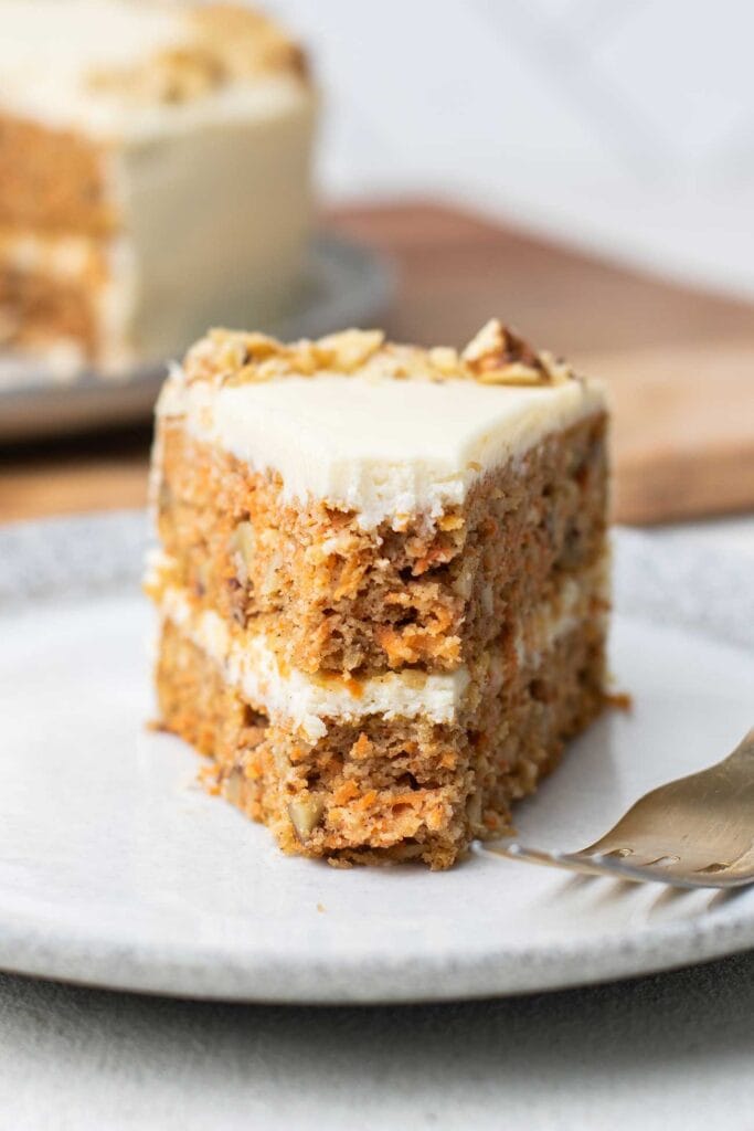 A slice of carrot cake with a bite taken out of the end.
