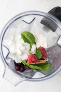 The ingredients for a greek yogurt smoothie shown in a blender.