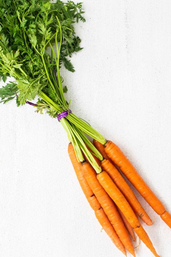 A bunch of carrots shown with the greens still attached.