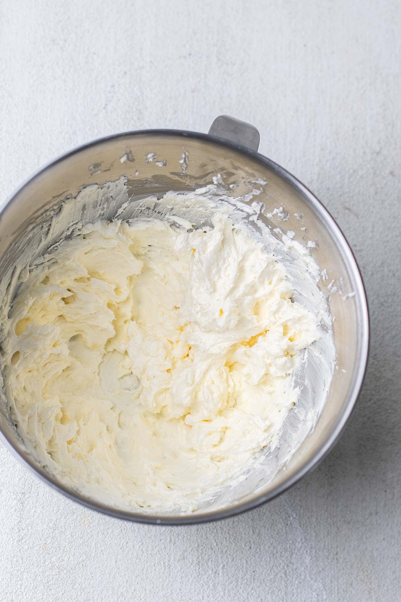 Cream cheese and butter shown whipped together in a bowl.