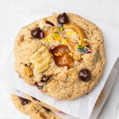 A stack of kitchen sink cookies with sprinkles, potato chips, and dark chocolate chips.