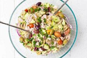 A brightly colored tuna quinoa salad in a glass bowl.