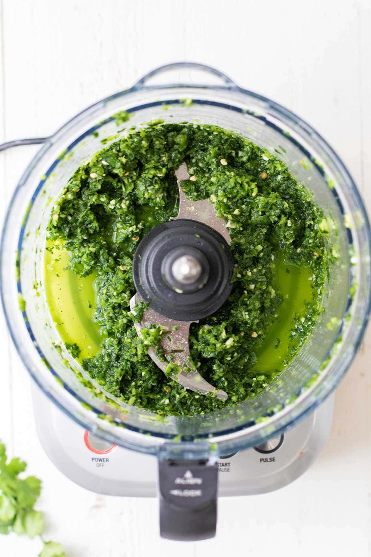 The peppers and cilantro in a food processor shown chopped.
