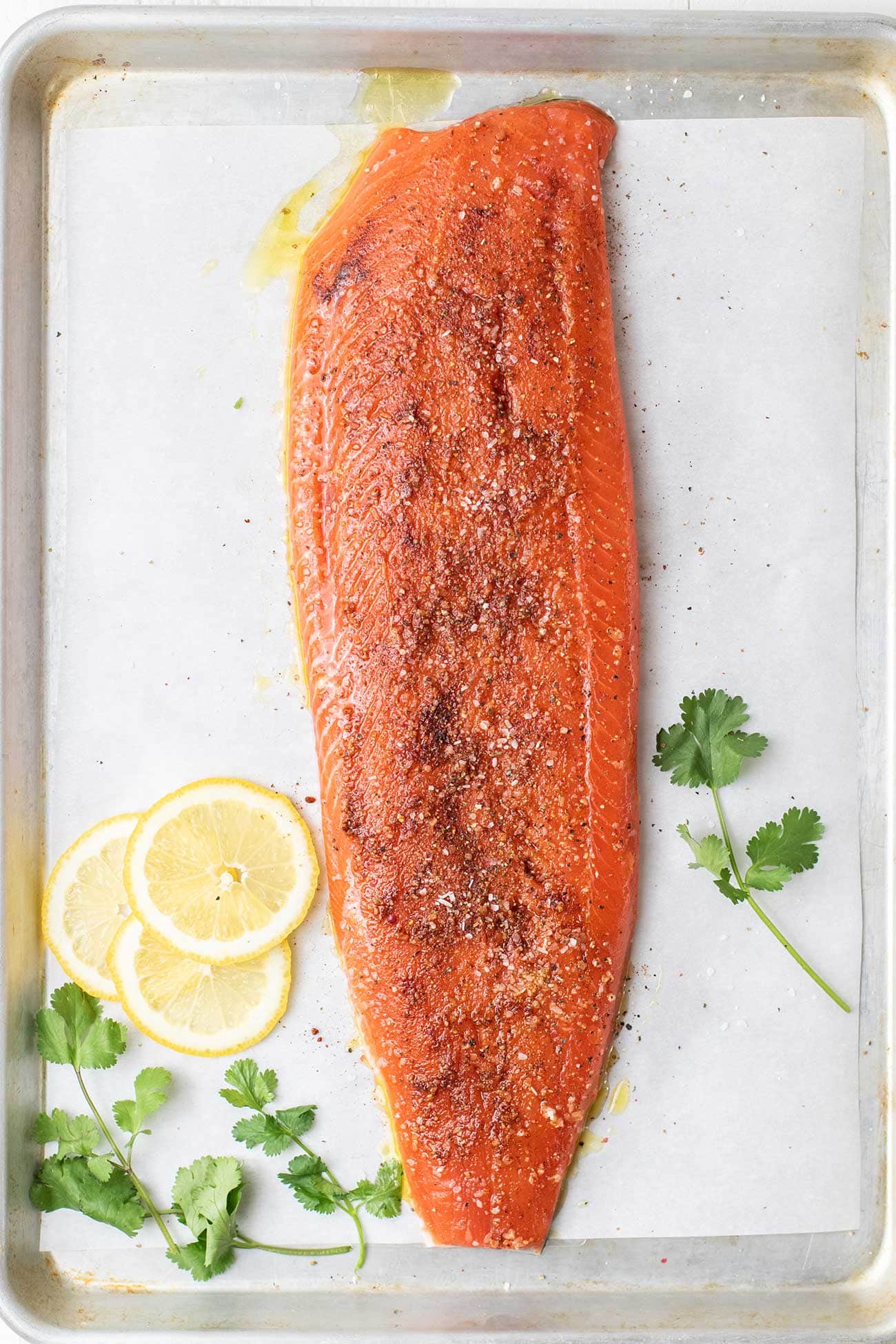A salmon filet on a baking pan with olive oil and spices rubbed in to it.