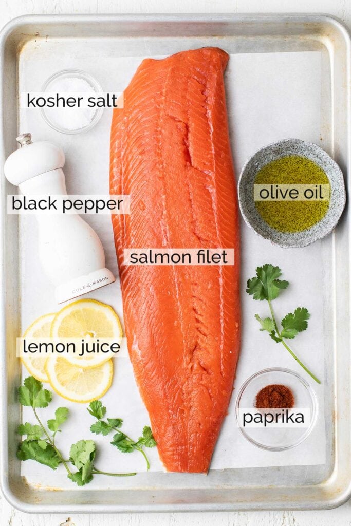 A salmon filet surrounded by the other ingredients needed to make slow roasted salmon.