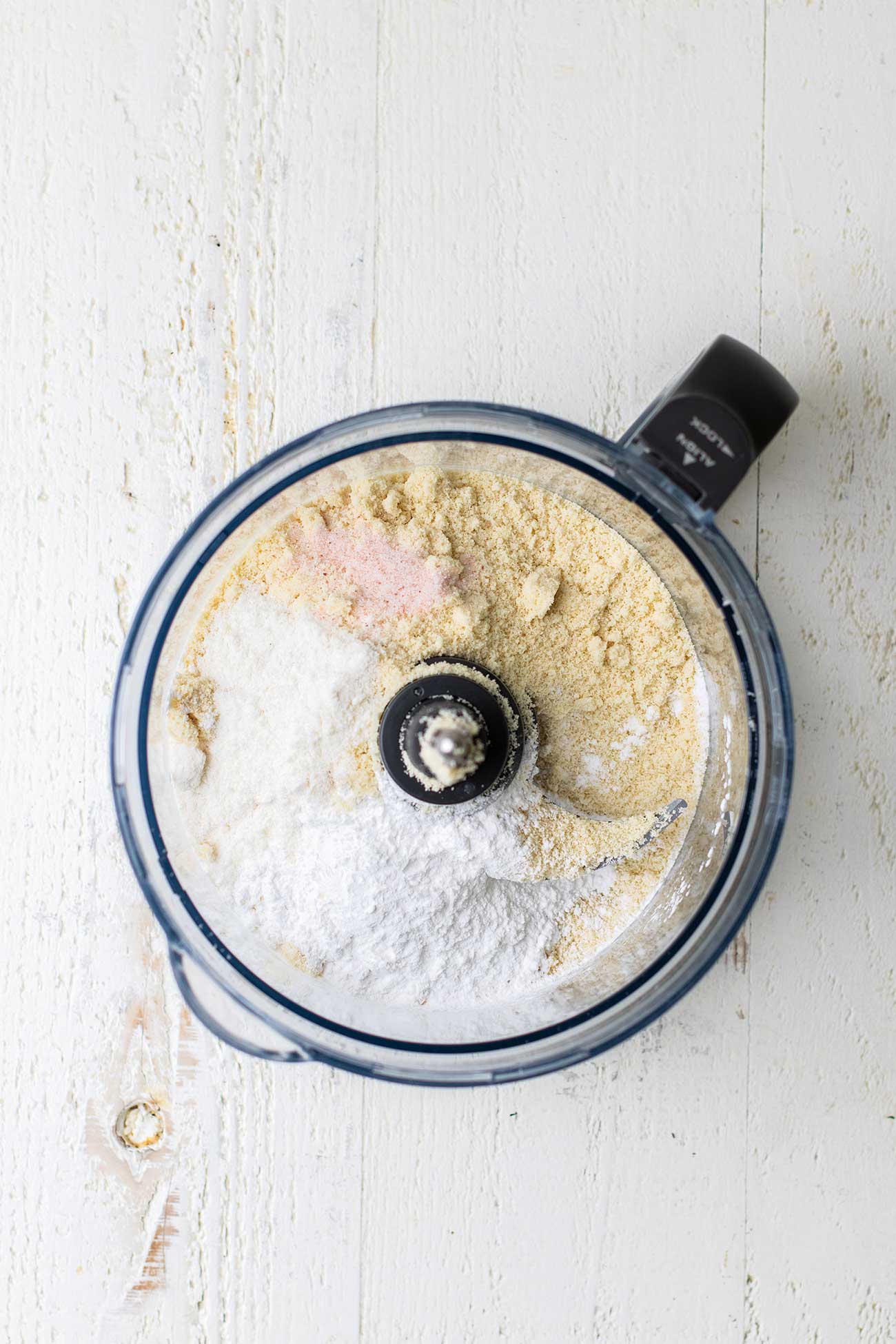 A food processor bowl with almond flour, coconut flour, arrowroot and salt.