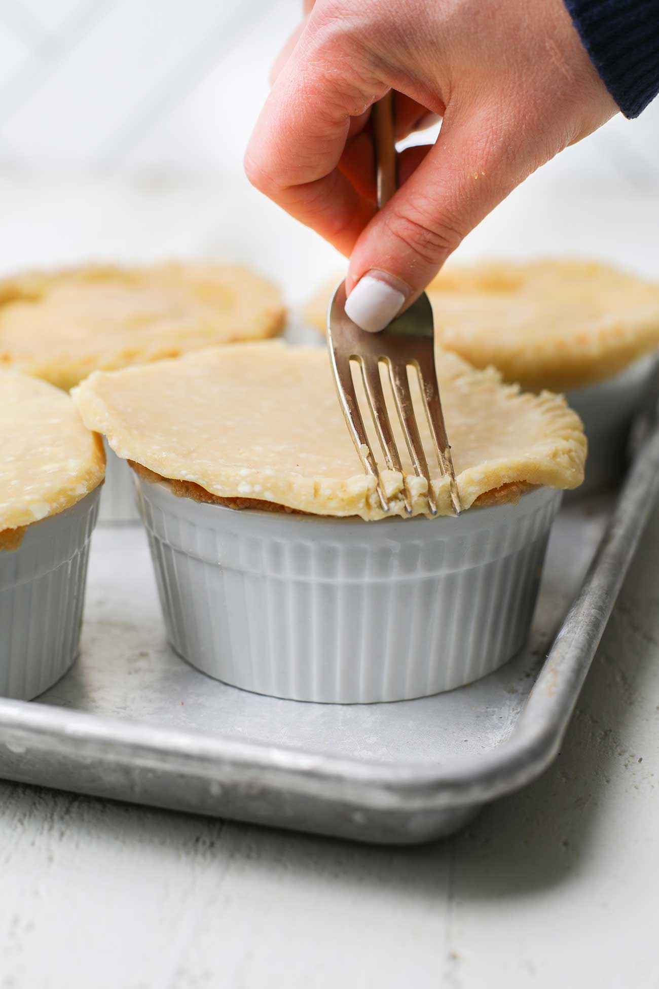 A fork pressing down a top pie crust.