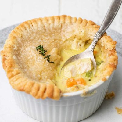 A gluten free chicken pot pie on a plate with a spoon scooping out some filling.