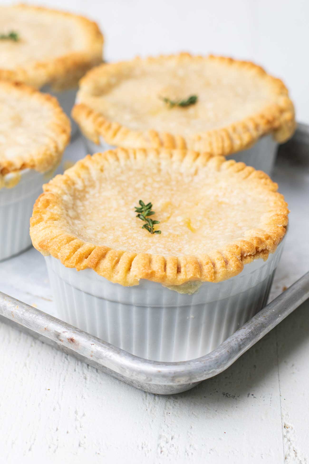 Chicken Pot pies shown with a golden brown crust garnished with thyme.