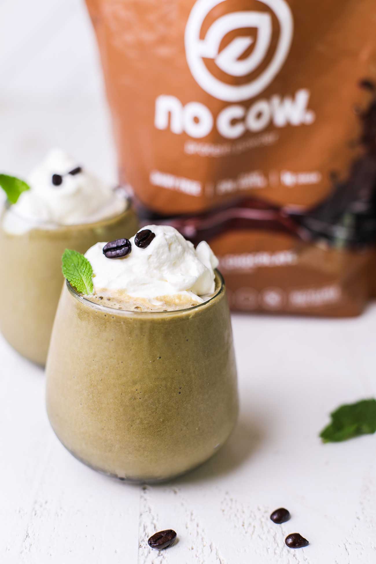 Two coffee smoothies garnished with whipped cream.