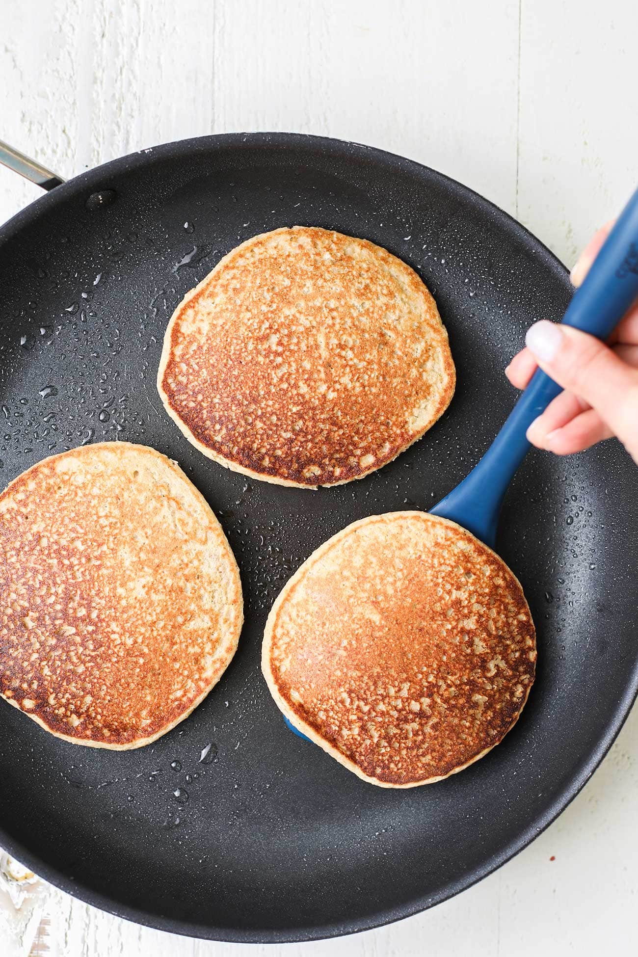 Golden pancakes shown being flipped in a skillet.