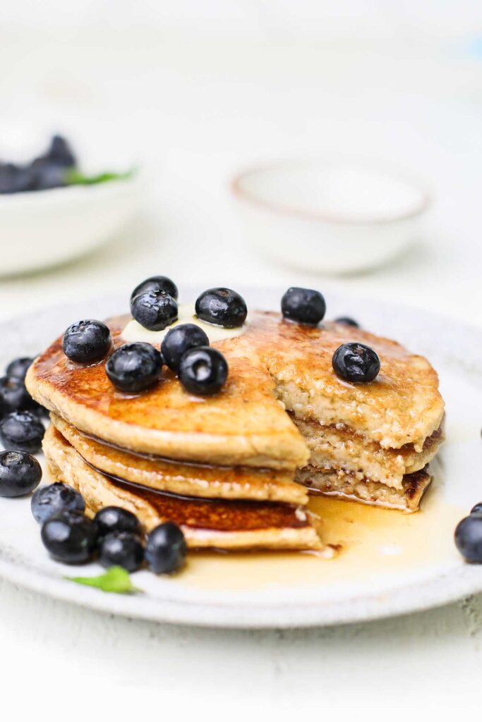 A plate of protein pancakes topped with blueberries and syrup.