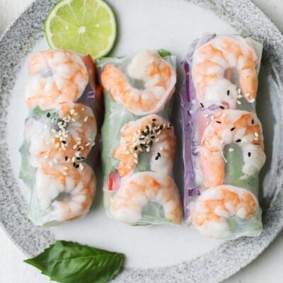 3 spring rolls shown with shrimp on a white plate.