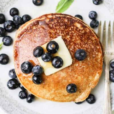 A stack of pancakes topped with butter and blueberries.