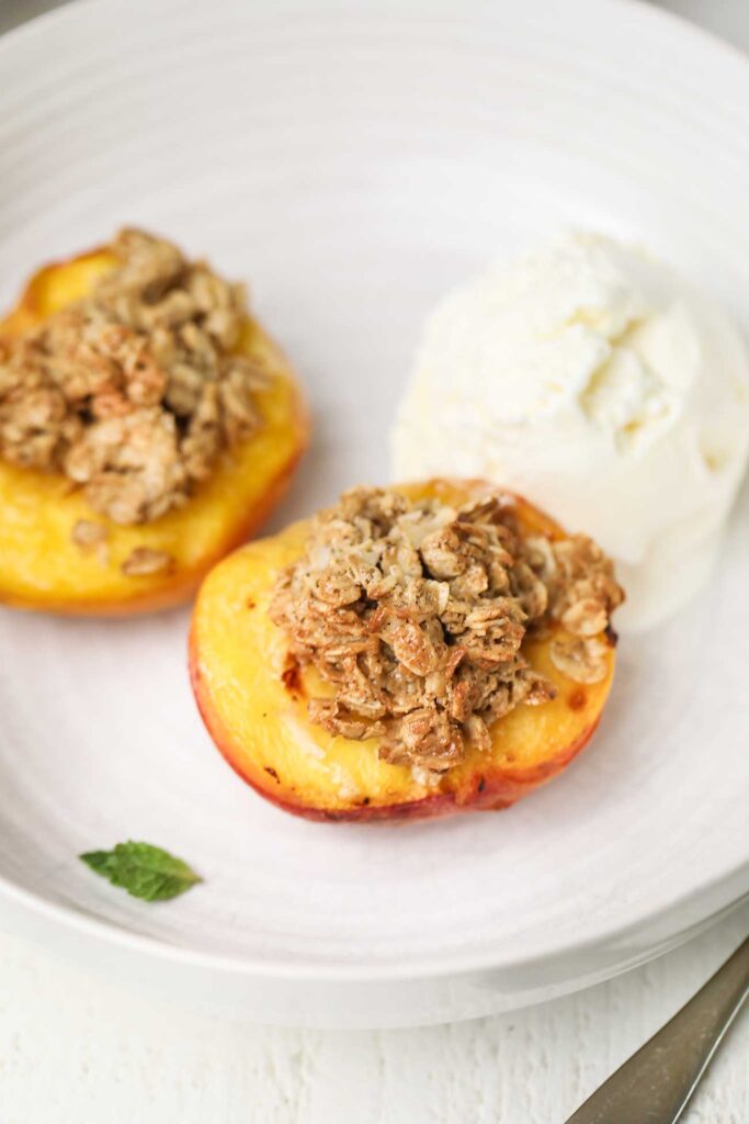 Two air fryer peaches shown with a crisp oat topping.