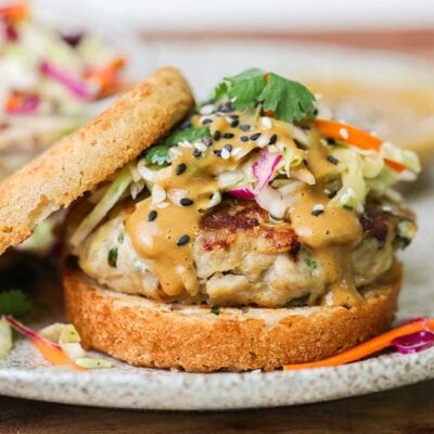 A close up look at a Thai chicken burger served on a bunch with Asian slaw.