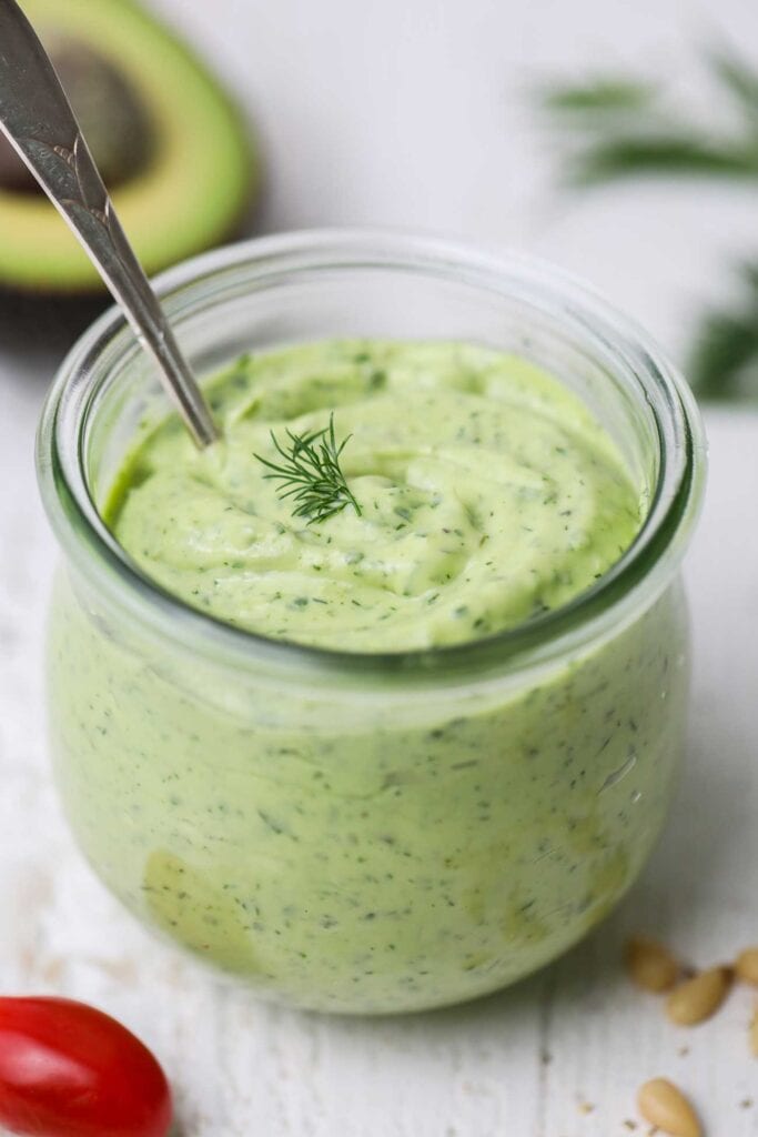 A jar filled with a thick avocado green goddess dressing.