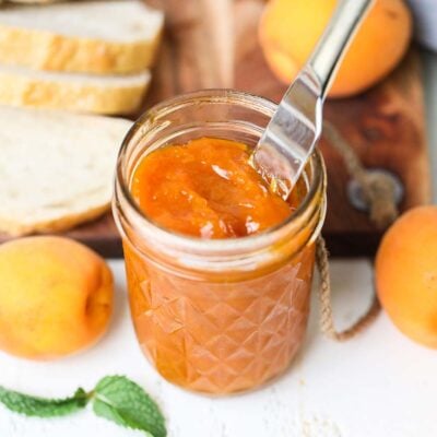 A jar of low sugar apricot jam with a knife sticking in to the jar.