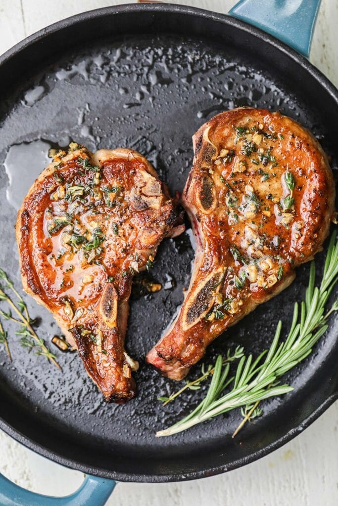 Two pork chops shown topped with an herb butter.