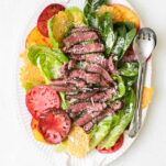 A platter with tomatoes, romaine lettuce, and steak.
