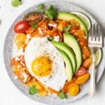 A plate of chilaquiles rojos topped with a sunny side up egg.